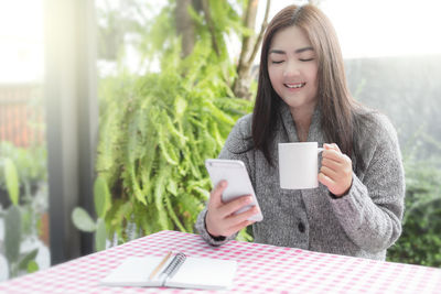 Young woman drinking coffee while sitting on table