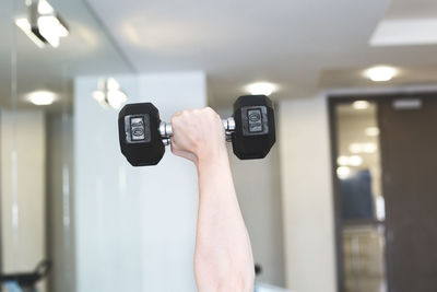 Cropped hand holding dumbbell in gym