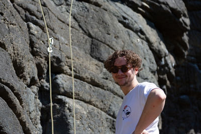Young man wearing sunglasses standing on rock