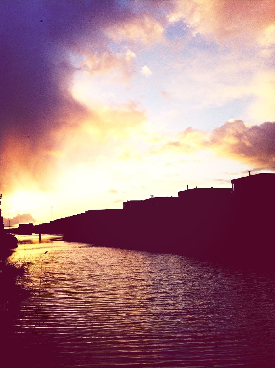 sunset, architecture, built structure, building exterior, water, waterfront, sky, cloud - sky, orange color, silhouette, rippled, river, reflection, cloud, scenics, city, beauty in nature, sun, nature, building