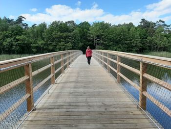 Rear view of man walking on footbridge