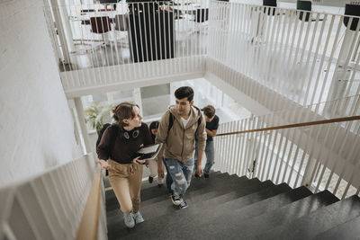 High angle view of students talking while moving up on steps in university