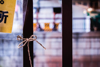 Cropped image of sign tied with string on metallic fence