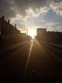 Railroad tracks in city against sky during sunset