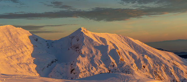 Snow-covered mountain grem at sunset