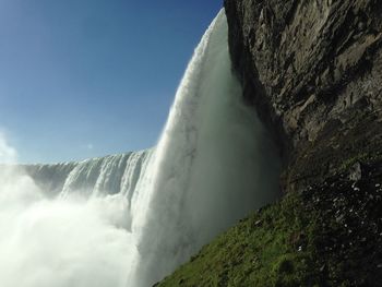 Low angle view of waterfall against sky