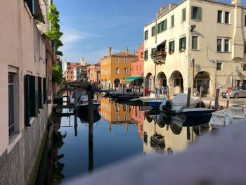 Boats moored in canal amidst buildings in city