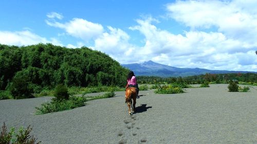 Woman with dog on mountain against sky