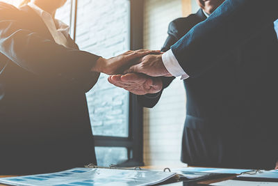 Businessmen stacking hands at desk in office