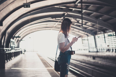 Side view of woman standing on escalator