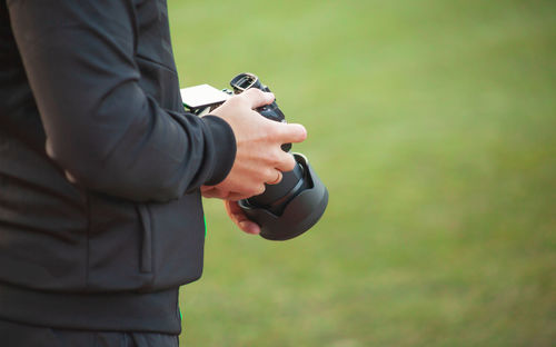 Midsection of man holding camera while standing on land