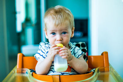 Portrait of cute baby boy drinking milk at home