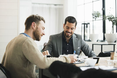 Smiling businessman with colleague at table during meeting in office