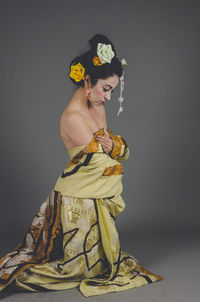 Midsection of woman with arms raised standing against pink background. geisha