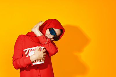 Man holding umbrella against orange yellow wall