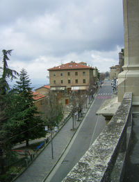 Road by buildings in city against sky