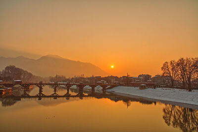 Bridge over river against sky during sunset