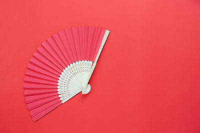 High angle view of folding fan over red background