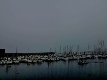 Sailboats in marina at harbor against clear sky