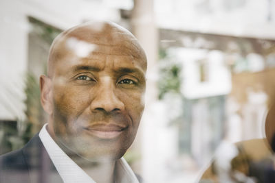 Portrait of confident mature entrepreneur looking away seen through glass window