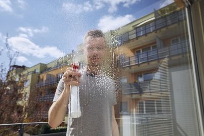 Low angle view of man holding glass against sky