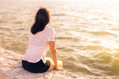 Rear view of woman sitting on beach