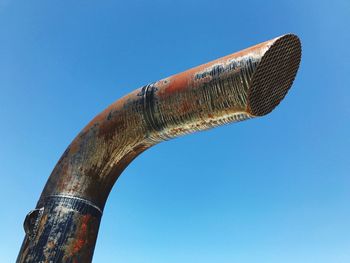 Low angle view of rusty metal against blue sky