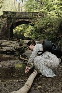 Rear view of woman sitting on rock