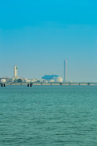 Sea by buildings against clear blue sky