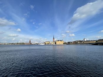 View of buildings by river against cloudy sky