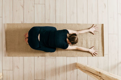 High angle view of man sleeping on hardwood floor