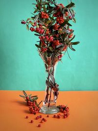 Close-up of red flower vase on table against wall