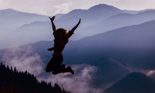 Girl jumping on the background of carpathian mountains