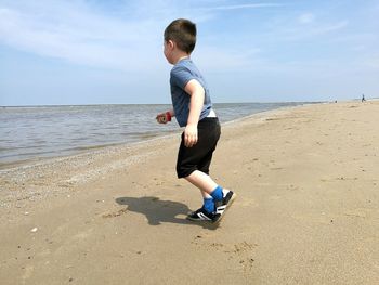 Full length of boy on beach against sky