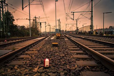 Railroad tracks against cloudy sky during sunset