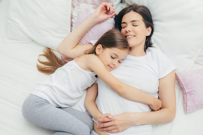 Mother and girl lying on bed