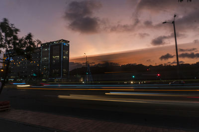 Light trails on road against sky at sunset