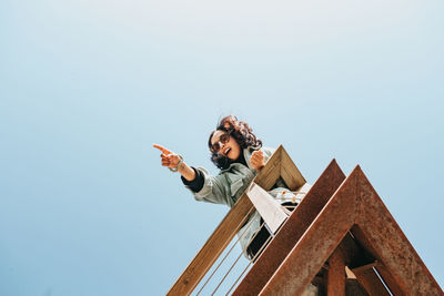 Low angle view of woman standing against clear sky