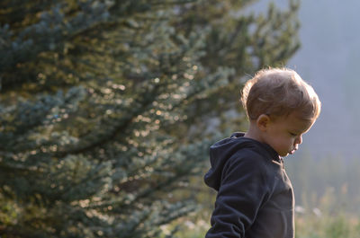 Side view of boy standing in forest