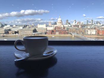 Coffee on table by buildings in city against sky