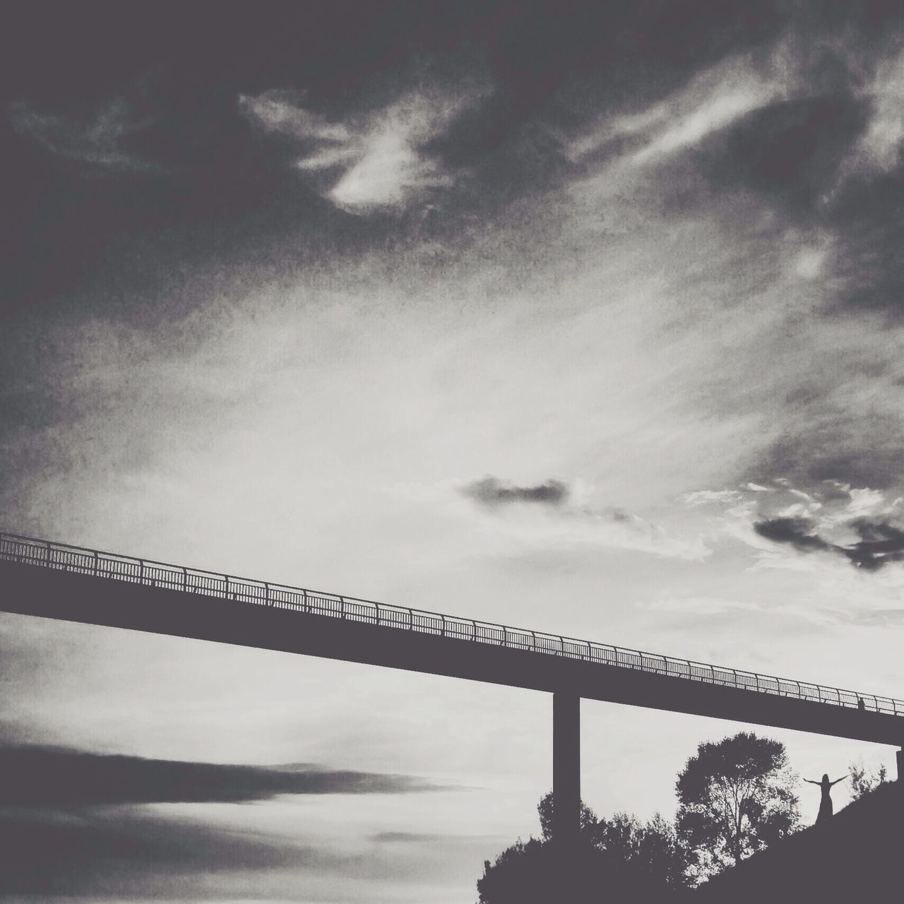 low angle view, sky, silhouette, cloud - sky, cloudy, built structure, cloud, architecture, dusk, connection, nature, outdoors, overcast, no people, tranquility, sunset, weather, day, tree, bridge - man made structure