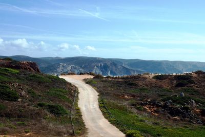 Road leading towards mountains against sky