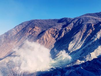 Scenic view of volcanic mountain against blue sky