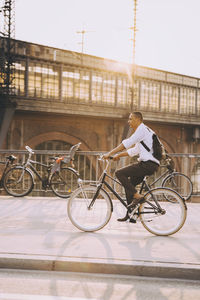 Man riding bicycle on city against sky