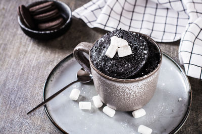 Quick chocolate cake mug with marshmallows on a plate on the table