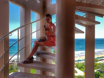 Full length of woman taking selfie from mobile phone while sitting on steps