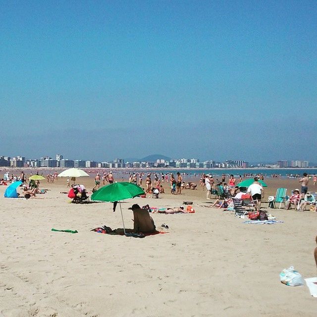 beach, sand, sea, shore, large group of people, vacations, water, relaxation, beach umbrella, clear sky, leisure activity, copy space, blue, parasol, person, summer, tourism, lifestyles, horizon over water