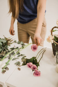 High angle view of woman standing by roses on table