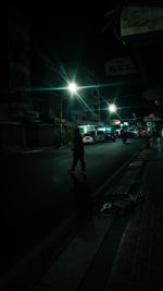 Man walking on illuminated street at night