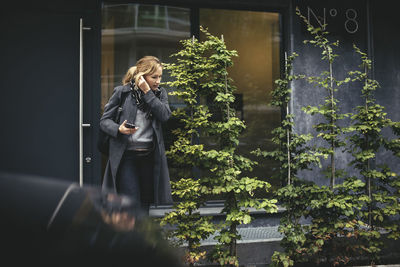 Mid adult businesswoman using hands-free device while crossing street